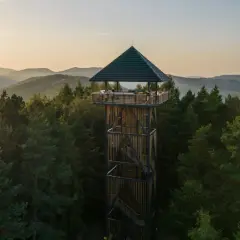 Wieża widokowa w otoczeniu lasu, z której rozpościera się panorama na beskid wyspowy szczyty.