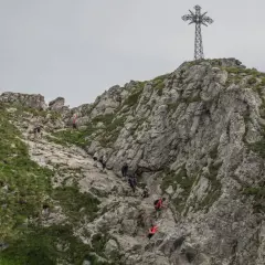 Grupa turystów wspina się po kamienistym zboczu Giewontu. Czy wejście na Giewont jest trudne? Trasa wymaga kondycji i ostrożności.
